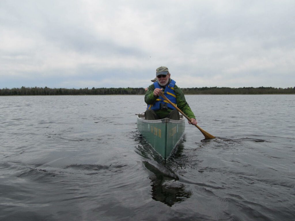 A man in a canoe on a lake on a cloudy day.