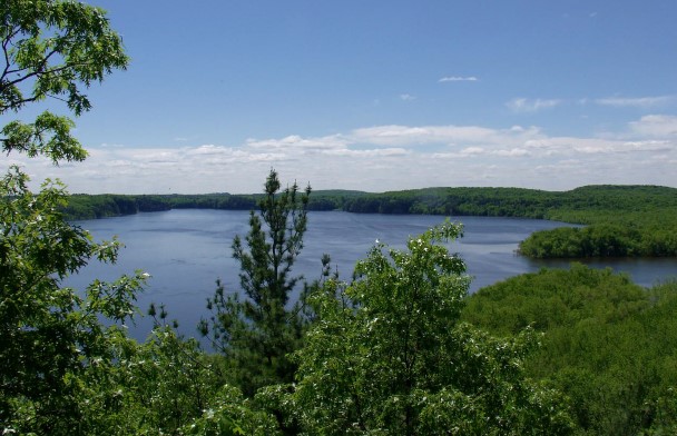 Louis' Bluff showing a view of a lake through trees from a birds-eye perspective.