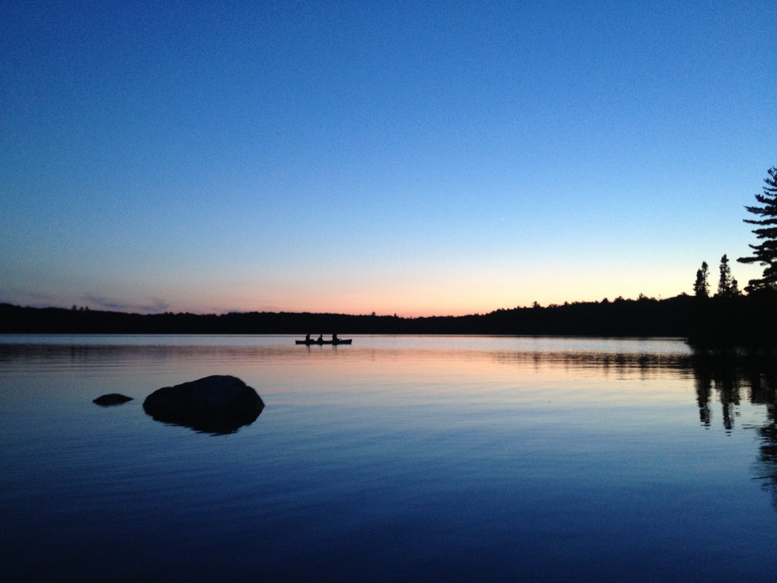 People in kayak in the middle of a lake while the sun sets