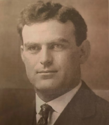 A sepia toned old photograph of a middle aged man in suit and tie.