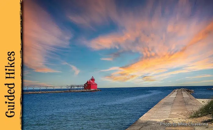 A small red lighthouse and long pier on Lake Michigan.