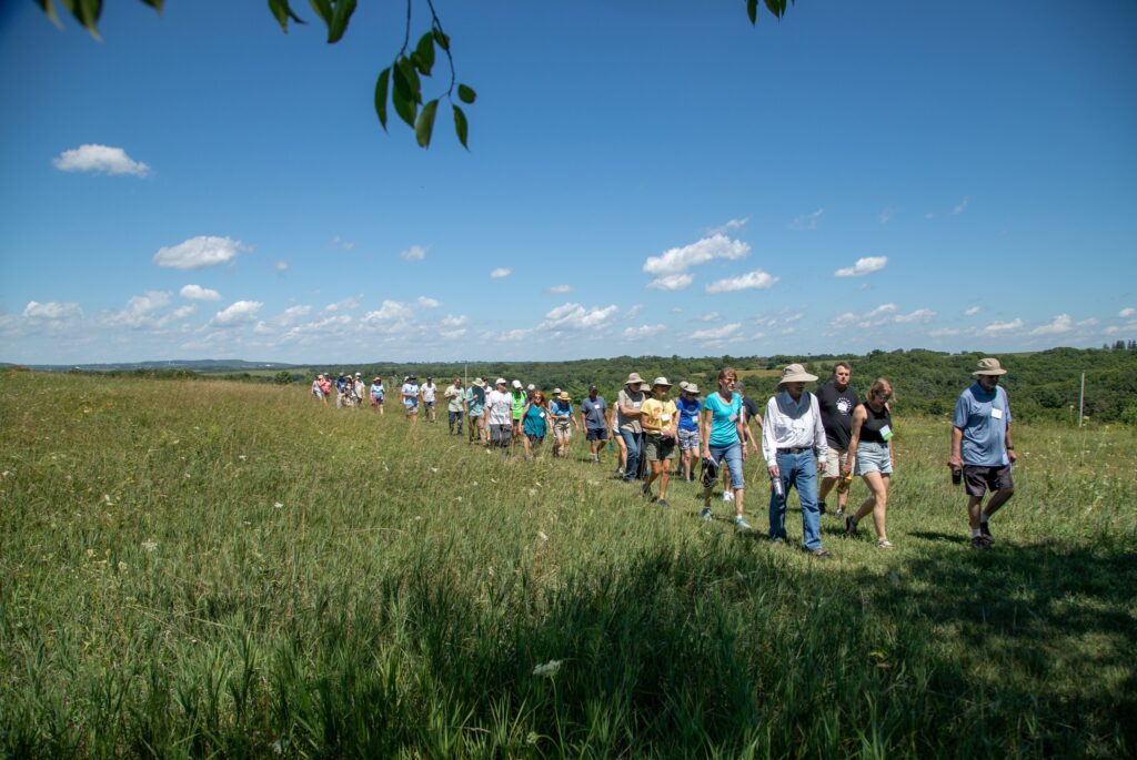 Dozens of people walking toward the camera on a hike during a summer day.