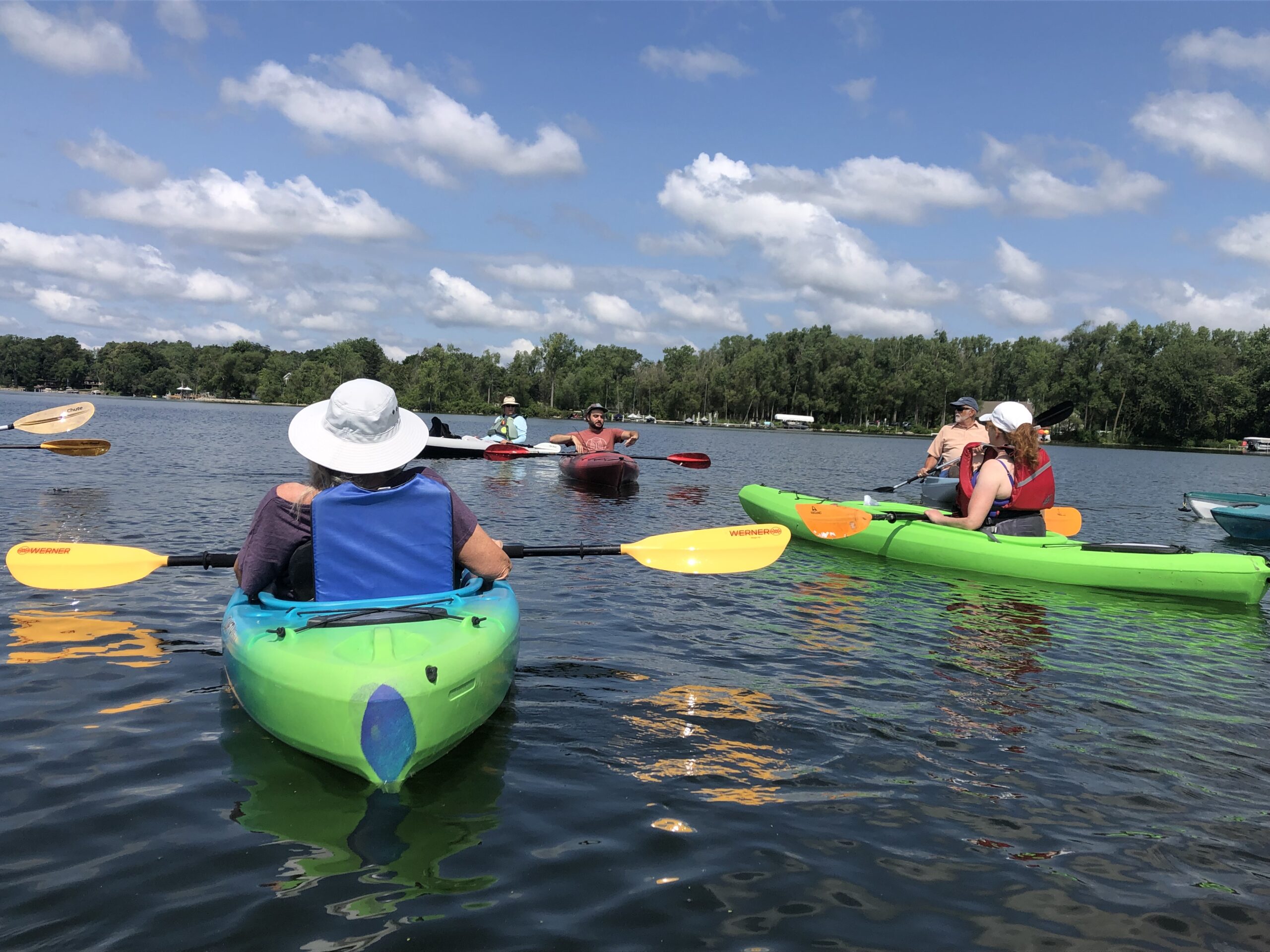 Several people in brightly colored canoes and kayaks on a Wisconsin lake.