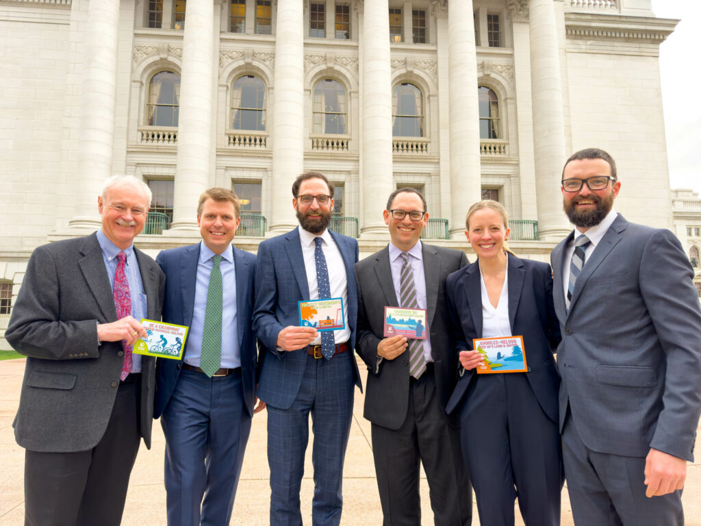 Six people in business suits in from the Wisconsin State Capitol holding Knowles-Nelson Stewardship Program postcards.