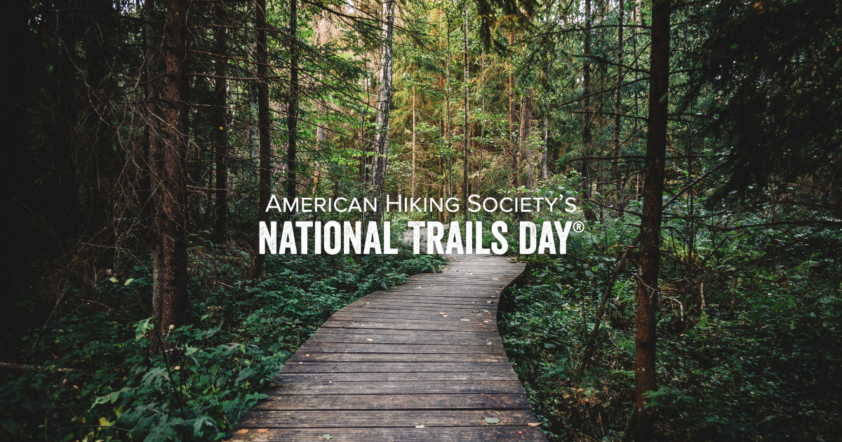 A photo of a boardwalk cutting through a pine forest with overlaid text, "American Hiking Society's National Trails Day".