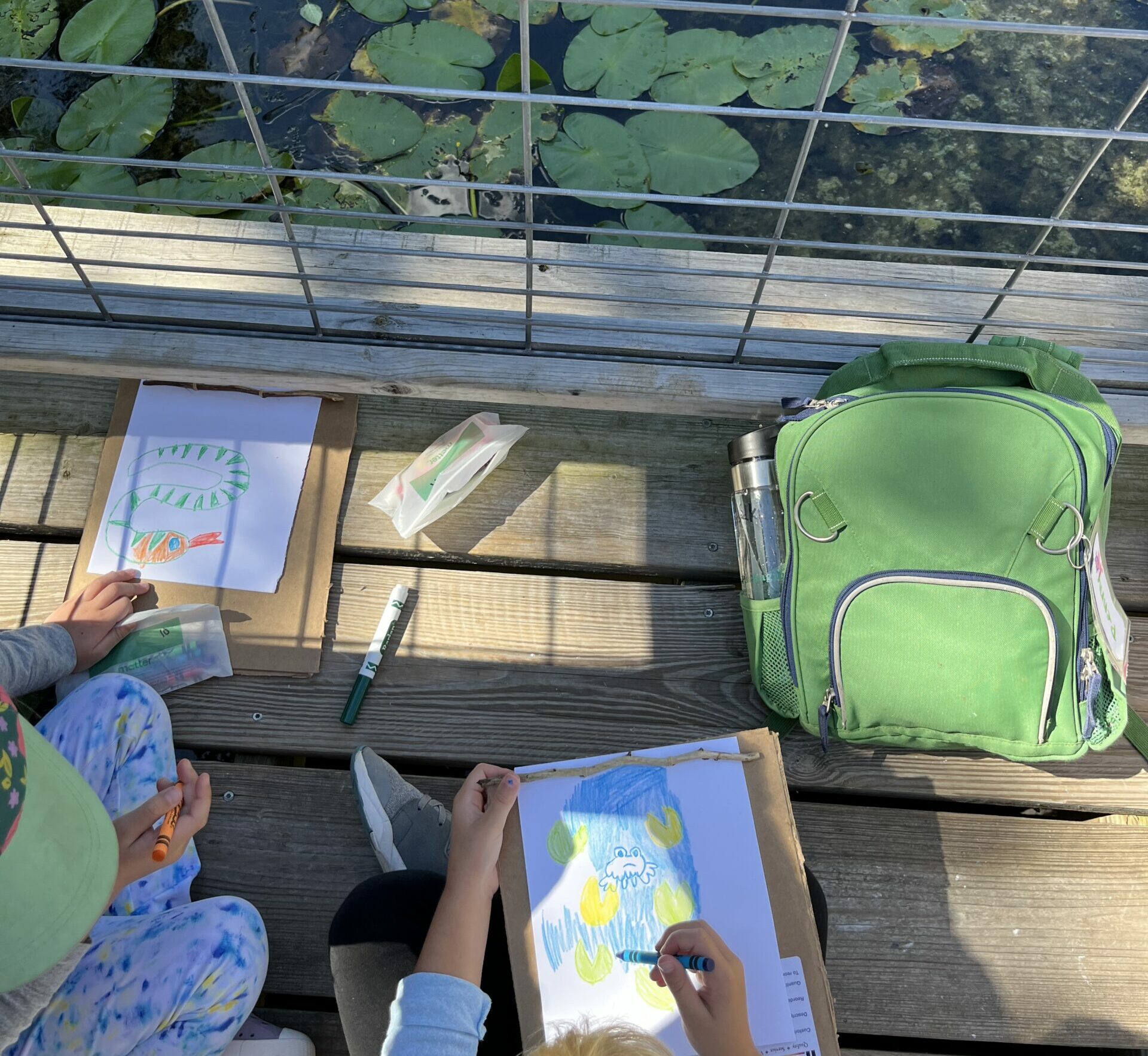Children coloring next to a pond