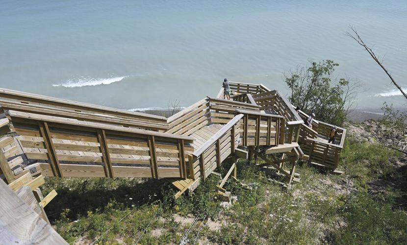 A steep, wooden stair case descends from a bluff down to Lake Michigan.