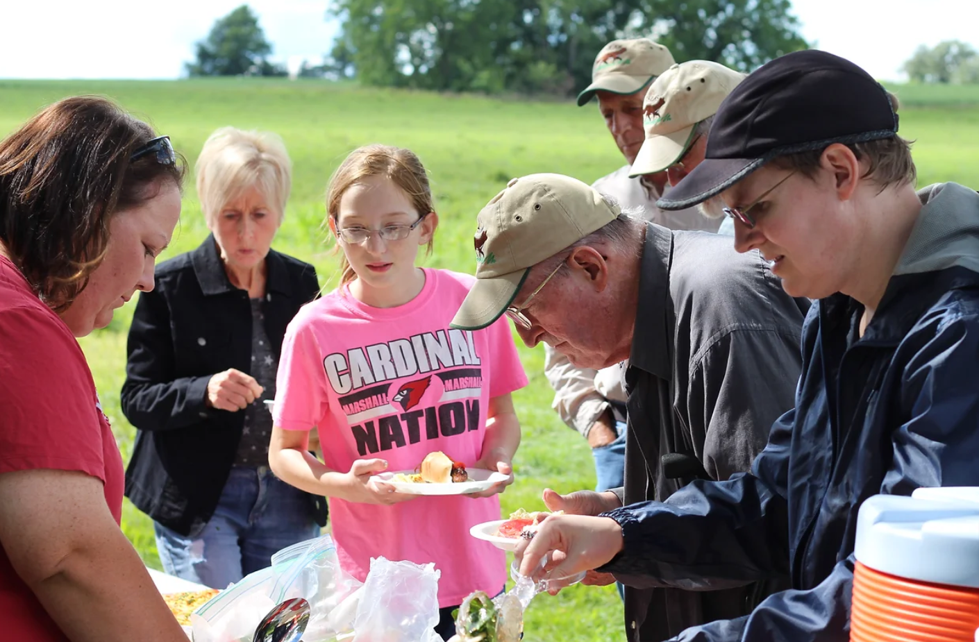 Kids and adults lining up for food at a picnic