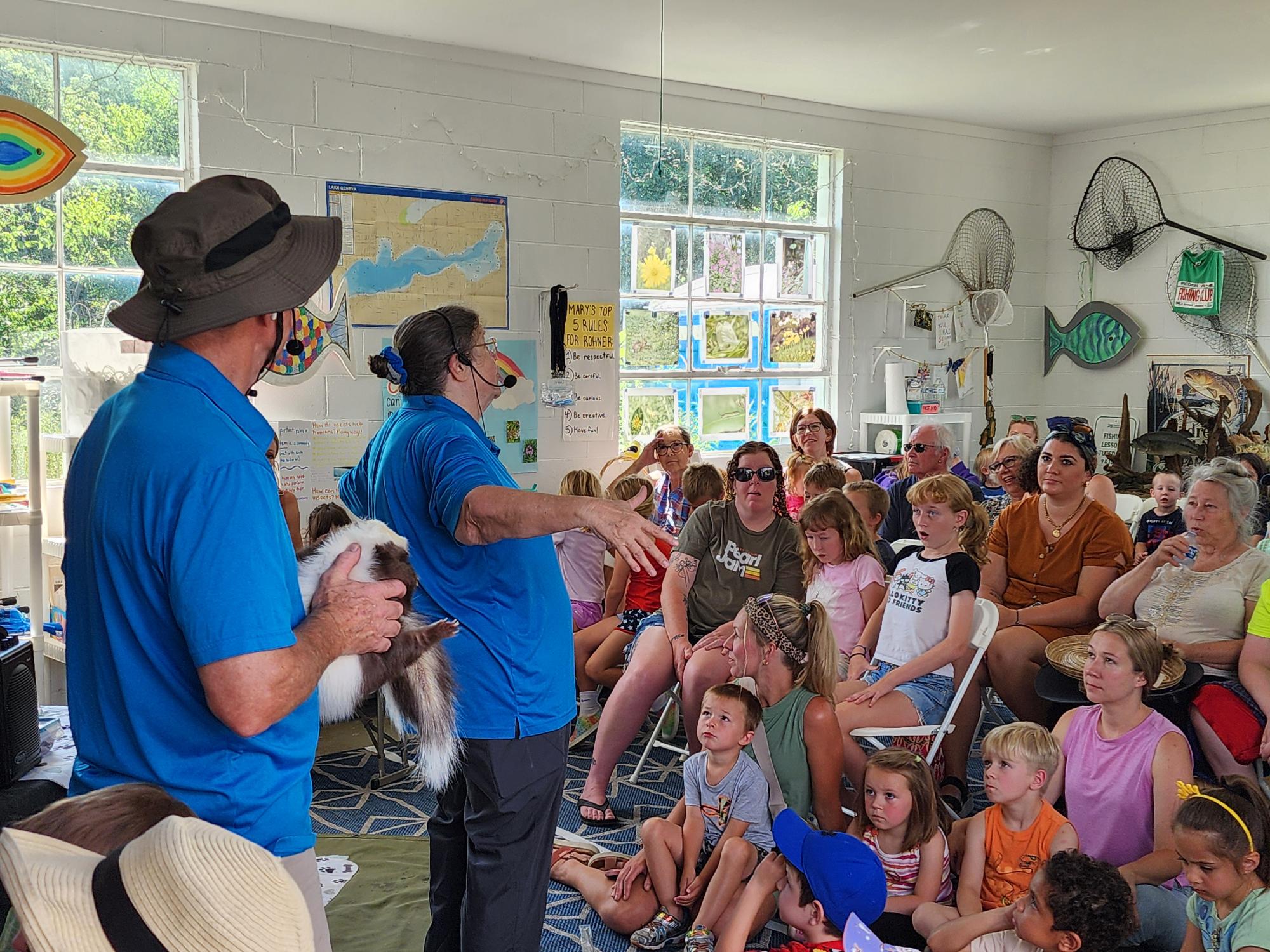 A group of kids and adults gathered inside for a presentation about animals.